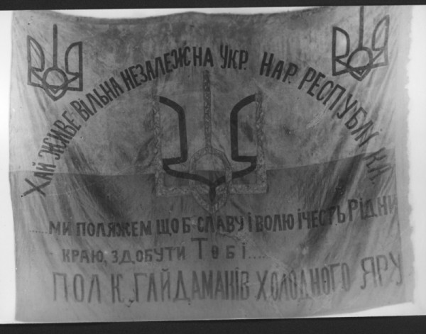 Синьо-жовтий прапор полку гайдамаків Холодного Яру. На ньому написи: “Хай живе вільна незалежна Укр. Нар. Республіка” і “Ми поляжем, щоб славу і волю і честь рідного краю, здобути тобі”  та зображення тризубів